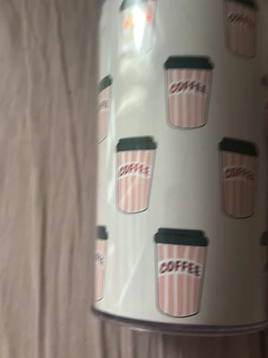 Burk med kaffemotiv - Säljer en vit burk med tryck av rosa och vita randiga kaffekoppar och texten 'COFFEE' på varje kopp. Perfekt för att förvara kaffe eller andra småsaker. Burken har ett modernt och lekfullt utseende.