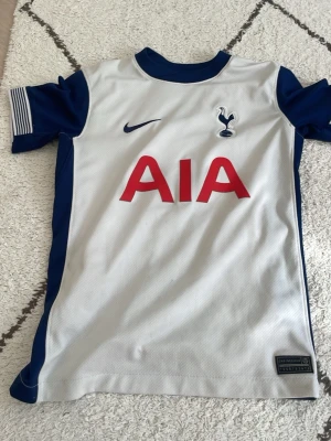 Tottenham Hotspur matchtröja Nike - Snygg Tottenham Hotspur matchtröja från Nike i vitt med mörkblå detaljer. Tröjan har klubbmärke och Nike-logga på bröstet samt AIA som sponsortryck i rött. Tillverkad i lätt och ventilerande material, perfekt för fotbollsträning eller match.Om ni är intresserade så kan vi diskutera priset. Storlek är 152 cm