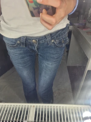 True Religion jeans – W23 💙 -  Snygga True Religion-jeans i storlek W23 med låg midja. Mörkblå tvätt med dekorativa svarta stenar längs sömmarna framtill som ger en stilren och exklusiv look. Jeansen är i sparsamt använt skick och har inga synliga hål eller större defekter. Detaljer: True Religion Storlek: W23 Låg midja Mörkblå tvätt Dekorativa svarta stenar framtill Sparsamt använt skick 📩 Hör gärna av dig om du vill ha fler bilder eller mått. Parfym fritt tvättmedel. Och inga djur i hemmet.