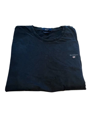 GANT långärmad t-shirt svart stl M liten logo - Svart långärmad tröja/t-shirt från GANT i storlek M. Stilren modell med liten broderad logo på bröstet. Väldigt lättmatchad och passar perfekt till clean/preppy/old money stil. Mycket bra skick!