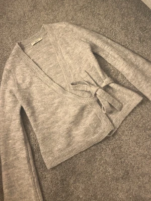 Grå omlottkofta från Gina Tricot - Mysig grå omlottkofta från Gina Tricot med knytband i midjan. 