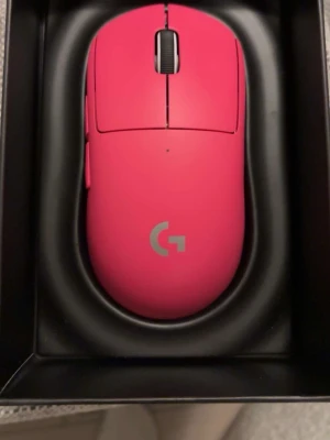 Logitech G Pro X Superlight rosa mus - Trådlös gamingmus från Logitech i en cool rosa färg med grått G-logotyp. Ergonomisk och lätt design, perfekt för snabba rörelser. Musen har två huvudknappar, scrollhjul och avancerad sensor på undersidan. Materialet är plast med matt finish.