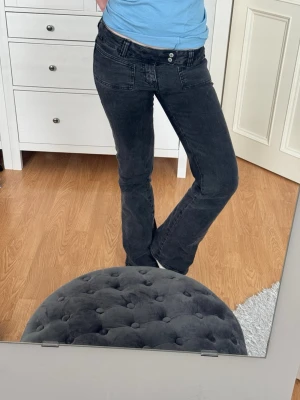 Svarta bootcut jeans med fickor - Säljer ett par svarta bootcut jeans med dubbla knappar och stora fickor fram. 