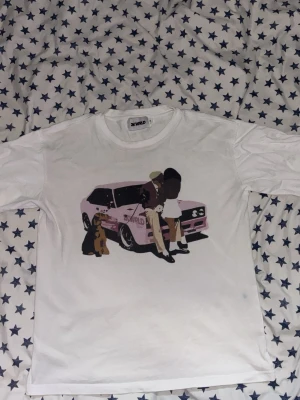 Vit t-shirt med tryck från 2K WRLD - Vit t-shirt från 2K WRLD med ett stort tryck framtill som visar två personer, en hund och en rosa bil. T-shirten har rund hals och korta ärmar. Perfekt för dig som gillar streetwear och coola motiv.