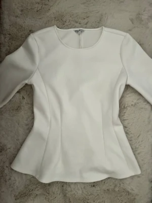 Vit figursydd blus från Object - Snygg vit blus från Object med rund halsringning och figursydd passform. Blusen har långa ärmar och lätt utsvängd nederkant som ger en feminin siluett. Perfekt att styla med jeans eller kjol för en clean look.