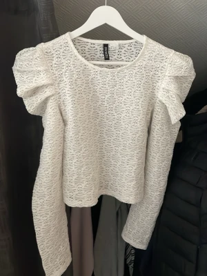 Vit spetsblus med puffärmar H&M - Superfin vit blus i spets från H&M med långa puffärmar och rund halsringning. Blusen har ett vackert spetsmönster och en rak passform som ger en trendig look. Perfekt att styla med jeans eller kjol för en snygg outfit.