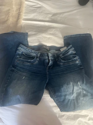 Blå bootcut jeans från LTB - Snygga blå jeans från LTB med lätt slitna detaljer och en simpel snygg detalj på bakfickorna. De är low waist och har rätt så raka men lätt utsvängda ben. Då jag säljer för de är för stora för mig.