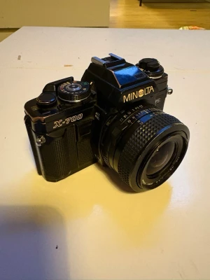 Minolta X-700 analog systemkamera - Klassisk svart Minolta X-700 systemkamera i retrostil. 3st kameror. Kameran har tydliga reglage, robust grepp och objektiv med manuell fokus. Perfekt för dig som gillar analog fotografering och vill ha full kontroll över inställningarna. Behövs nya aaaa batterier i laddaren men funkade prima för ca 1-2 månader sedan.