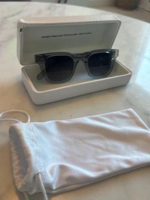 Grå transparenta solglasögon - Snygga solglasögon med transparent grå båge och mörka glas. Rektangulär form som ger en modern vibe. Kommer med vit förvaringspåse och hårt fodral. Perfekta för att lyfta din stil i sommar.