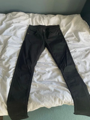 Svarta Tiger of Sweden jeans strl 30/32 - Svarta jeans från Tiger of Sweden i modellen slim. Strl 30/32. De är i bra skick utan missfärgningar och hål. Skulle behövas användas lite bara då de är lite skrynkliga sedan tvätt. Hör av er vid frågor och funderingar!