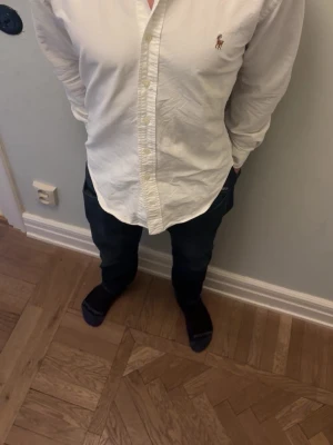 Vit skjorta från Ralph Lauren - Klassisk vit skjorta från Ralph Lauren med broderad logga på bröstet. Skjortan har fin passform och är storlek S slimfit. Modellen på bilden är 171 och väger 62 kg 