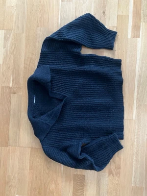 Svart stickad tröja från Gina Tricot - Svart stickad tröja från Gina Tricot med ribbad struktur och avslappnad passform.