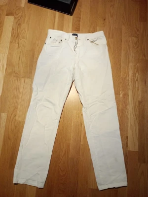 Vita raka jeans från PL&CO - Snygga vita jeans från PL&CO med rak passform och klassisk femficksdesign. Jeansen har bälteshällor, knappgylf och är tillverkade i ett mjukt bomullstyg. Perfekta för en clean och fräsch look.