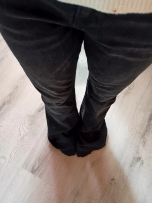 Svarta bootcut jeans med utsvängda ben - Snygga svarta bootcut jeans med utsvängda ben och klassiska bakfickor. Jeansen har hällor för skärp och en läderpatch bak i midjan. Perfekta för dig som gillar retrostil och vill ha ett par jeans med cool siluett.använda endast en gång annars är dem helt nya och köptes för 350.