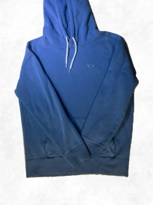 Blå hoodie från Hollister - Snygg blå hoodie från Hollister med klassisk känguruficka. En äldre model i xs men fortfarande i bra skick!