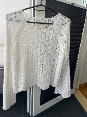 Vit virkad stickad tröja HM - Säljer en vit stickad tröja med virkat mönster och långa ärmar. Tröjan har en lös passform och är tillverkad i ett mjukt, luftigt material som ger en bohemisk känsla. Perfekt för lager på lager och snygg till både jeans och kjol.
