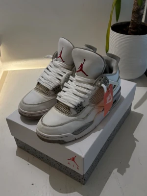 Air Jordan 4 Retro white oreo - Säljer ett par Air Jordan 4 Retro sneakers från Nike i vitt med grå och röda detaljer. Skorna har klassisk siluett, meshpaneler och Jumpman-logga på plösen. Perfekta för dig som gillar streetwear och vill sticka ut med en ikonisk modell.