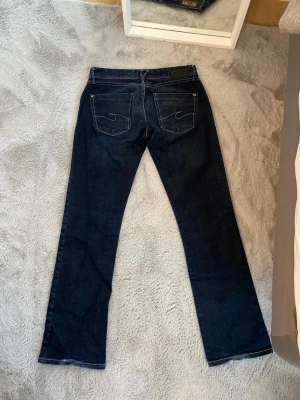 Lågmidjade jeans - Säljer ett par snygga mörkblåa lågmidjade jeans från märket Cross i storlek 29/32. Köpta på vinted, fint skick. Innerbenslängd: 76 cm Midjemått rakt över: 36 cm