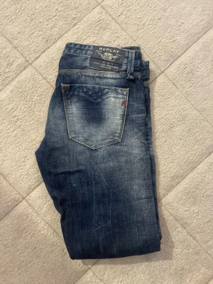 Slim jeans från Replay, blå denim - Snygga blå slim fit jeans från Replay med slitna detaljer och klassisk femficksmodell. Jeansen har en tvättad look och kontrastsömmar, tillverkade i mjuk denim som sitter skönt. Perfekta för dig som gillar en avslappnad men trendig stil.