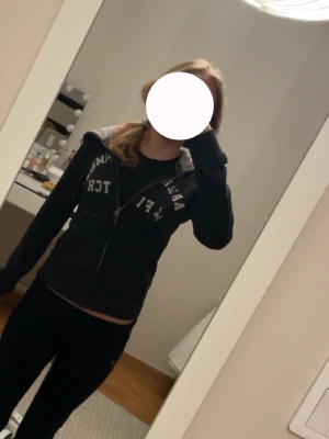 Mörkblå zip hoodie från Abercrombie & Fitch - Mörkblå zip hoodie med dragkedja från Abercrombie & Fitch. Stor vit logga på bröstet, huva med dragsko och två fickor framtill. Perfekt för en chill och avslappnad stil. Klassisk college-vibe och skönt material.