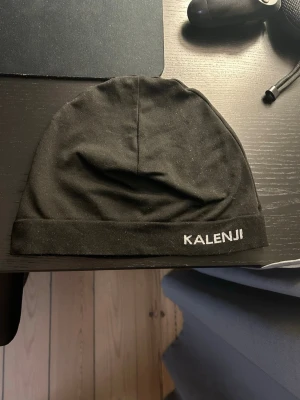 Svart mössa från Kalenji - Säljer en svart mössa från Kalenji med enkel och stilren design. Mössan är tillverkad i ett tunt, stretchigt material som passar perfekt för träning eller löpning. Diskret logga broderad framtill. Sitter tajt på huvudet och är lätt att bära.