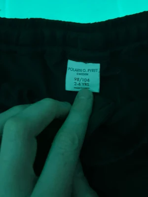 Svarta sportshorts från Polarn O. Pyret - Svarta sportiga shorts från Polarn O. Pyret med elastisk midja och diskret P.O.P Sport-tryck på benet. Perfekta för aktiva dagar och träning. Klassisk och enkel design som funkar till det mesta.