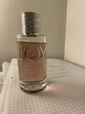 JOY by Dior parfym 90 ml - JOY by Dior är en lyxig parfym i en rund glasflaska med silverfärgad metallkork. Vätskan är ljusrosa och flaskan har tydlig logga i silver. Perfekt för dig som gillar eleganta och fräscha dofter. Cirka 90ml kvar. 