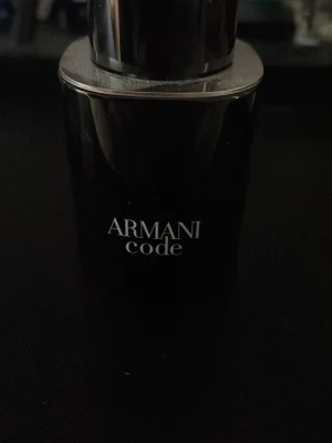 Armani Code parfym - Snygg parfymflaska från Armani Code med elegant svart design och silverfärgat lock. Flaskan har en stilren och modern form som känns lyxig och passar perfekt på parfymhyllan. Doften är ikonisk och populär bland många. 40ml kvar 