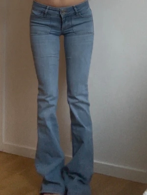 Ljusblå bootcut jeans - Säljer ett par ljusblå bootcut jeans med klassisk femficksdesign och utsvängda ben. Jeansen har normalhög midja och är tillverkade i mjukt denimtyg. Perfekta för en avslappnad och trendig look.
