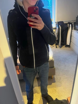 Marinblå väst med huva Zadolo - Snygg marinblå från Zadolo med stor huva och två dragkedjeförsedda fickor framtill. Västen har quiltad design och dragkedja hela vägen upp. Perfekt för lager-på-lager och chill stil. Västen är helt ny