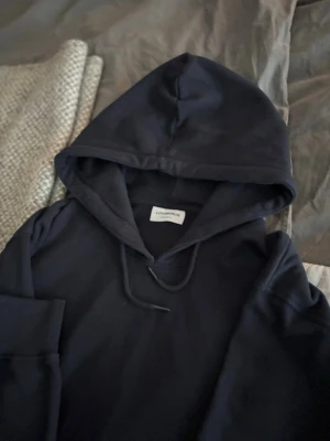 Marinblå hoodie från Lindbergh - Snygg svart hoodie från Lindbergh med klassisk huva och dragsko. Tillverkad i mjukt material som känns skönt mot huden. Perfekt för dig som gillar en clean och enkel stil. Hoodien har långa ärmar och ribbade muddar.