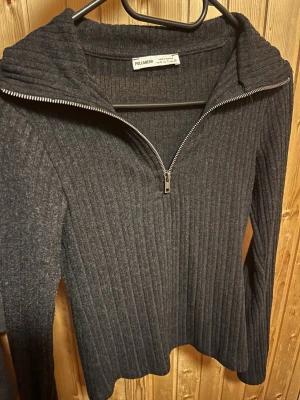 Mörkgrå ribbstickad tröja Pull&Bear - Tunn långarmad tröja från Pull&Bear med halv dragkedja framtill och hög krage. Perfekt för lager på lager eller sommarkvällar.