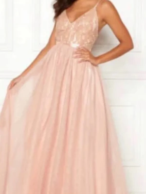 Ljusrosa långklänning med spets - Romantisk ljusrosa långklänning med tunna axelband och v-ringad spetsliv. Kjolen är i flera lager av tunt tyg som ger en svepande känsla. Perfekt för bal eller student. Använd 1 gång så är i mycket fint skick.