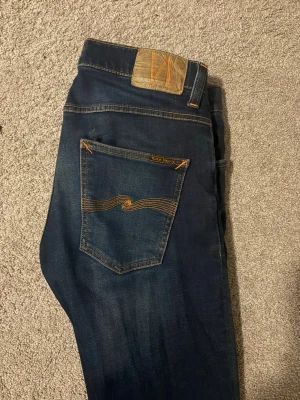 Nudie jeans - Snygga mörkblå nudie jeans med snygg tvätt. Storlek är 30/32 modell: Grim Tim