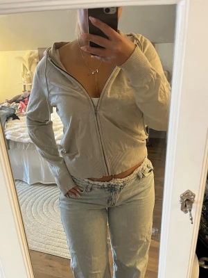 Beige stickad zip-hoodie med luva - Säljer en beige stickad hoodie med dragkedja och huva. Modellen är croppad med ribbade muddar vid ärmslut och nederkant. Perfekt för en chill och avslappnad stil. Materialet känns mjukt och lätt, passar till jeans eller tights.🥰🥰