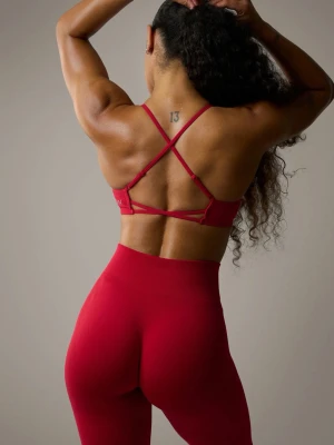 Röd sport-bh med korsade band - Snygg röd sport-bh från ICANIWILL med smala korsade axelband i ryggen. Bh:n är tillverkad i ett stretchigt material som passar perfekt för träning och ger bra stöd. Enkel och stilren design med logotyp på sidan.