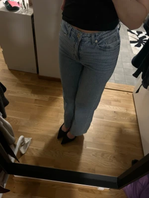 Ljusblå raka jeans med hög midja - Säljer ett par ljusblå jeans med rak passform och hög midja. Klassisk femficksmodell med knapp- och dragkedjegylf. Jeansen har en avslappnad look och är tillverkade i denim, perfekt till en enkel topp eller hoodie. Knappt använda