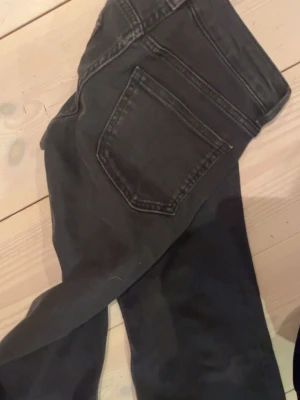 Svarta lågmidjade jeans från H&M Divided - Säljer ett par svarta lågmidjade jeans från H&M Divided i storlek 34. Klassisk femficksmodell med bootcut ben och lågmidja. Jeansen är tillverkade i bomull med lite stretch för extra komfort. Perfekta till alla typer av outfits!