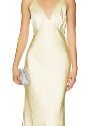 Ljusgul  långklänning i silke - Elegant långklänning i ljusgult silke med smala axelband, djup v-ringning och öppen rygg. Klänningen har en slät, glansig yta och följsam passform som ger en lyxig känsla. Nypris på denna klänningen är 3200.