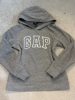 GAP vintage hoodie XS - Vintage grå hoodie från GAP med stor vit logga framtill. Superliten fläck på ärmen (se sista bilden), annars bra skick💕