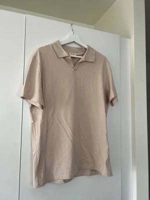 Beige t-shirt med krage Filippa K - Stilren beige t-shirt från Filippa K med klassisk krage och korta ärmar. Tillverkad i mjuk bomull för en skön känsla och avslappnad passform. Perfekt till jeans eller shorts för en enkel men snygg look. Använd vid få tillfällen, så gott som ny! 
