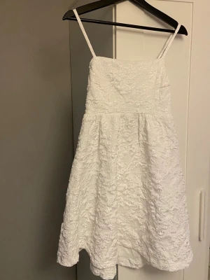 Vit klänning - Superfin vit kort klänning med smala axelband och strukturerat tyg. Klänningen har en lätt utsvängd kjol och är perfekt för student, konfirmation eller skolavslutning. Enkel och stilren design med justerbara band. Köpt på Sellpy men är från Bubbleroom (har lappen kvar). Hel och ren, helt oanvänd. 