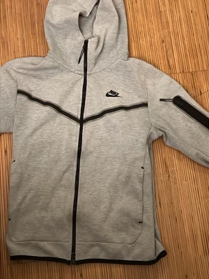 Grå Nike Tech fleece kofta - Nike teech kofta snygg kofta syd längs ut på armen annars bra skick nypris 1200kr snabb affär !! 