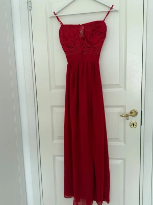 Röd klänning med spets - En lång röd klänning med spets. Finns inbyggnda shorts under klänningen. 