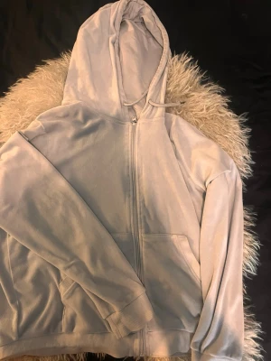 Ljusblå zip hoodie med huva - Ljusblå hoodie med dragkedja och stor huva. Tröjan har ribbade muddar, två fickor framtill och snören i huvan. Perfekt för en avslappnad och chill look. Materialet känns mjukt och bekvämt mot huden.