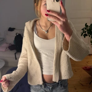 Beige ribbad zip-kofta - Säljer en beige ribbad kofta med dragkedja och huva. Koftan har långa ärmar och är gjord i ett mjukt stickat material. Pris kan diskuteras vid snabb affär💌