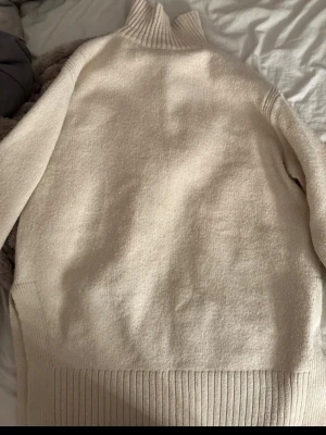 Beige stickad polotröja - Mysig beige stickad oversized polotröja med bred ribbstickad mudd vid ärmslut och nederkant. Tröjan har hög krage och är tillverkad i ett mjukt material som passar perfekt för kyliga dagar. Enkel och stilren design som är lätt att matcha.