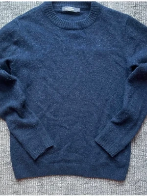 Mörkblå stickad tröja Dressmann - Mörkblå stickad tröja från Dressmann med rund halsringning och ribbade muddar vid ärmslut och nederkant. Tröjan är i ett mjukt material och har en klassisk, enkel design som passar till många olika stilar. ⚠️Liten i storleken och sitter åt ⚠️