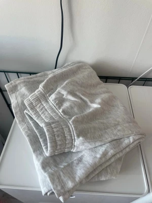 Ljusgrå mjukisbyxor med resårmidja - Säljer ett par ljusgrå mjukisbyxor med bred resår i midjan. Byxorna har en avslappnad passform och är tillverkade i mjukt bomullsmaterial. Perfekta för chill dagar hemma eller när du vill vara bekväm. Utsvängda ben.