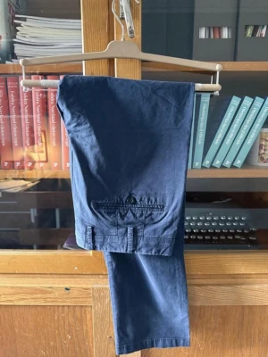 Mörkblå Loro Piana Chinos  - Säljer ett par mörkblå chinos från det exklusiva italienska märket Loro Piana då de inte längre passar mig. Notera att byxorna är producerade av Loro Piana själva, alltså inte endast annat märke som använt sig av deras tyg.   Storlek 48 men skulle personligen säga att de sitter mer som 46.  Endast använda ett fåtal tillfällen och därav i väldigt fint skick utan något slitage eller tecken på användning.   Nypris ligger kring 7000kr.  Kan skickas eller hämtas på Östermalm.